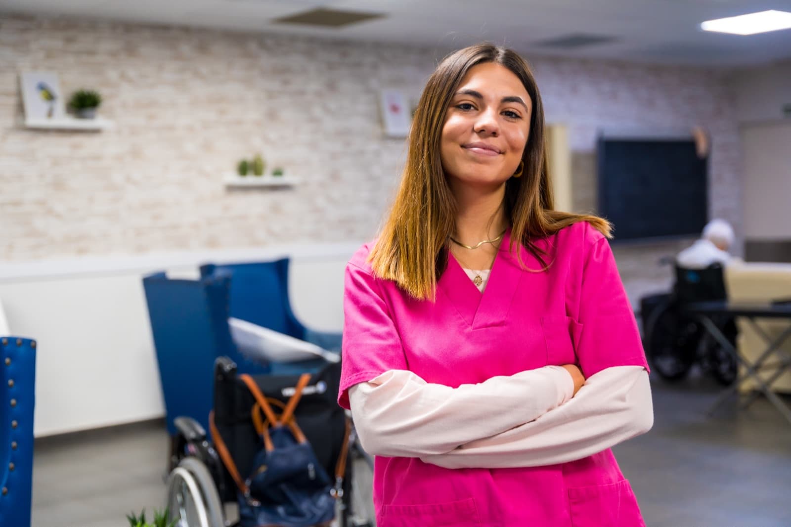 Cuidadora con uniforme rosa de brazos cruzados