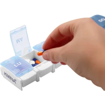 mano abriendo tapa de pastillero semanal con compartimentos visibles