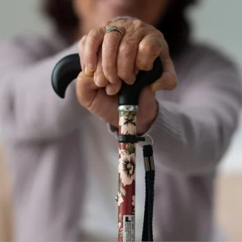 mano de persona mayor sujetando baston con diseno floral