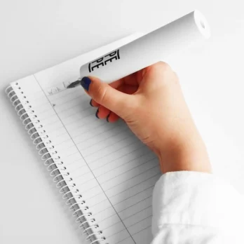 mano escribiendo con guia de escritura adaptada en libreta