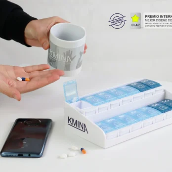 pastillero con compartimentos y vaso medidor sobre una mesa