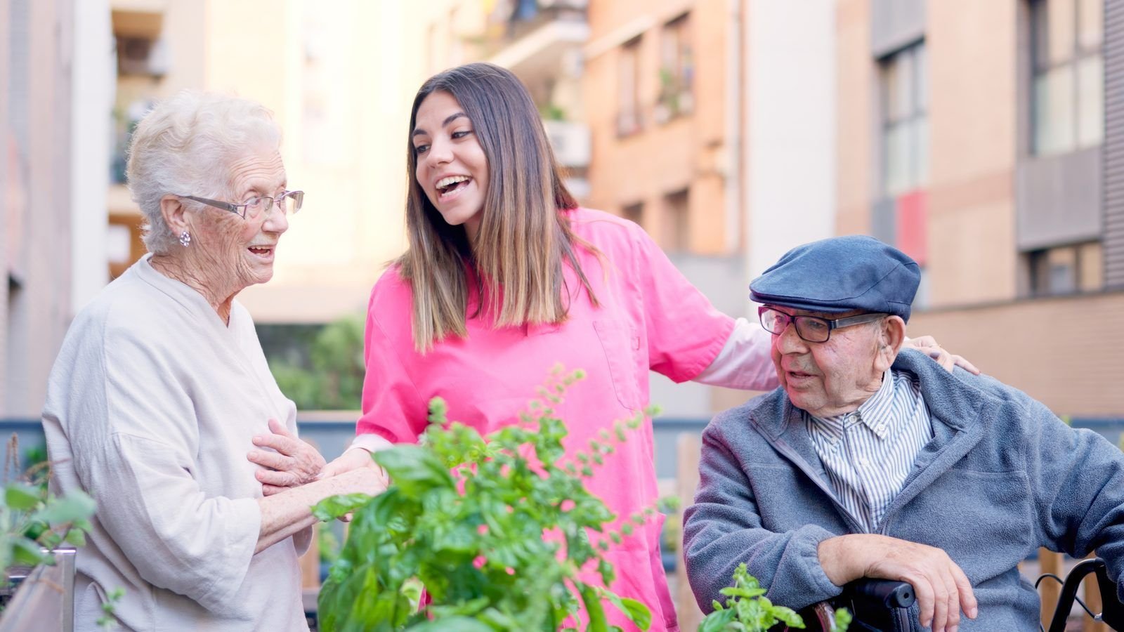 Cuidadora con dos personas mayores cuidando plantas en un huerto