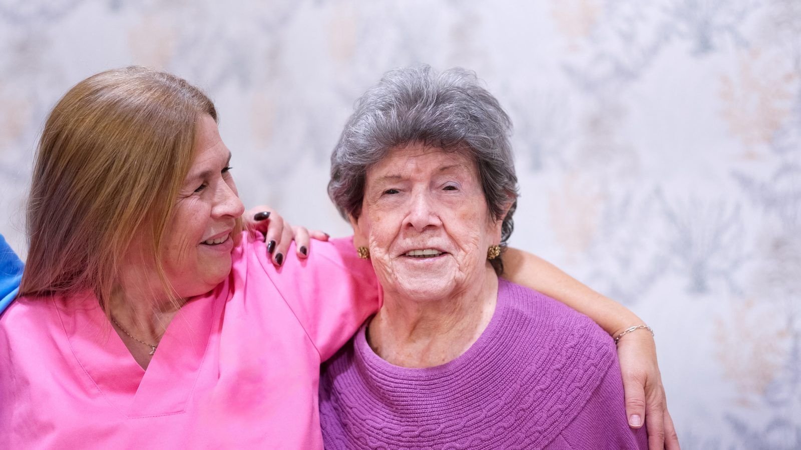 Cuidadora abrazando a una señora mayor sonriente
