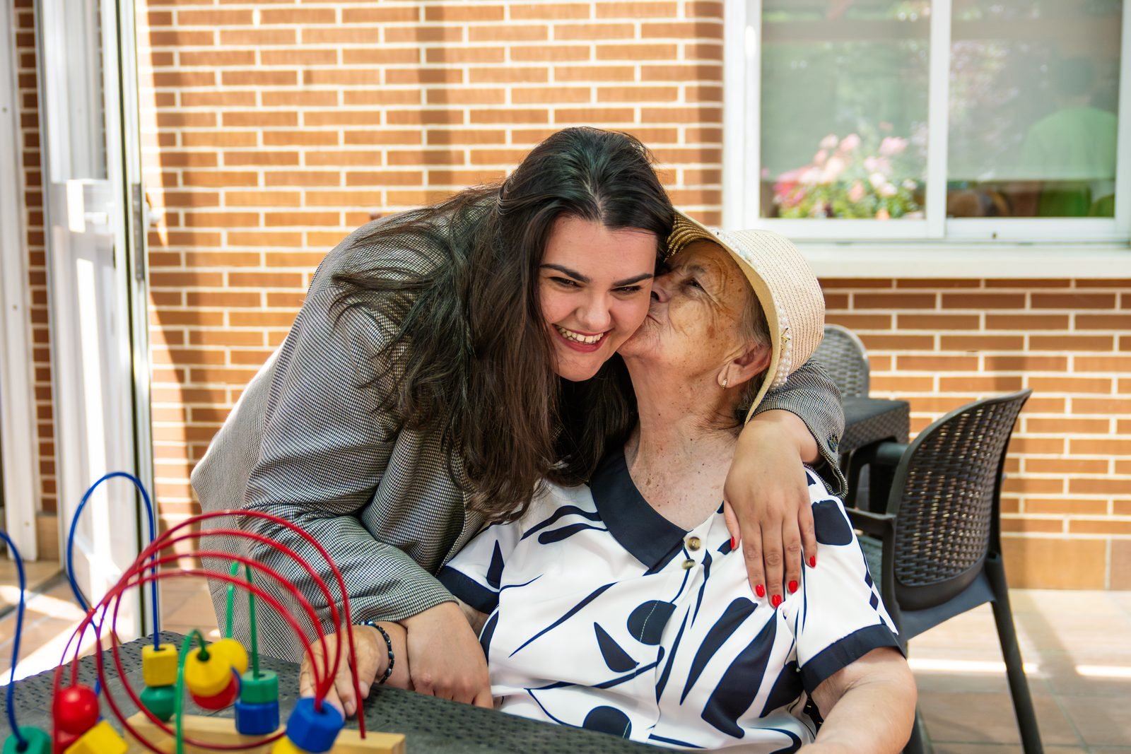 Nieta abrazando a su abuela sentada en el jardín