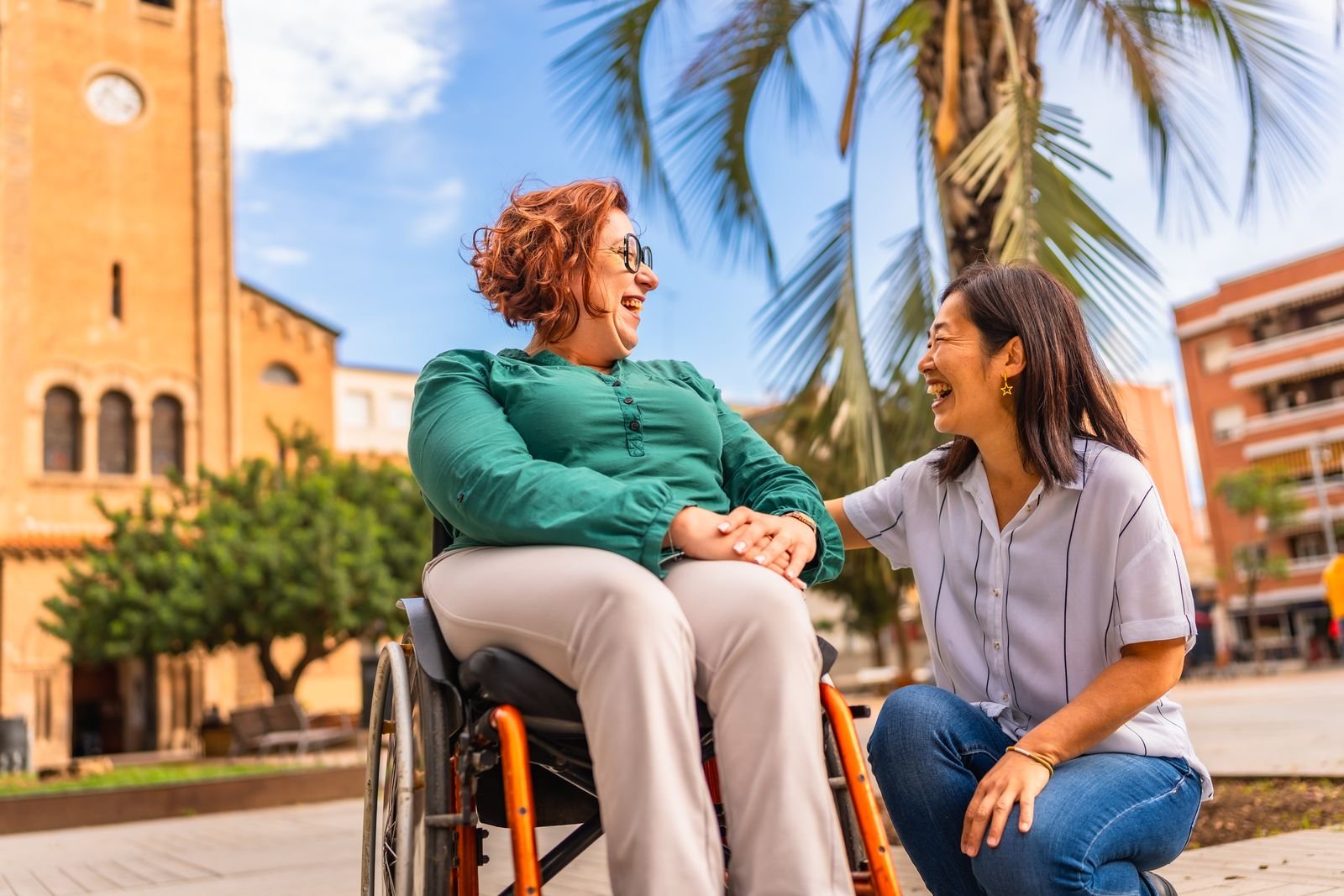 Cuidadora charlando con una señora en silla de ruedas en una plaza
