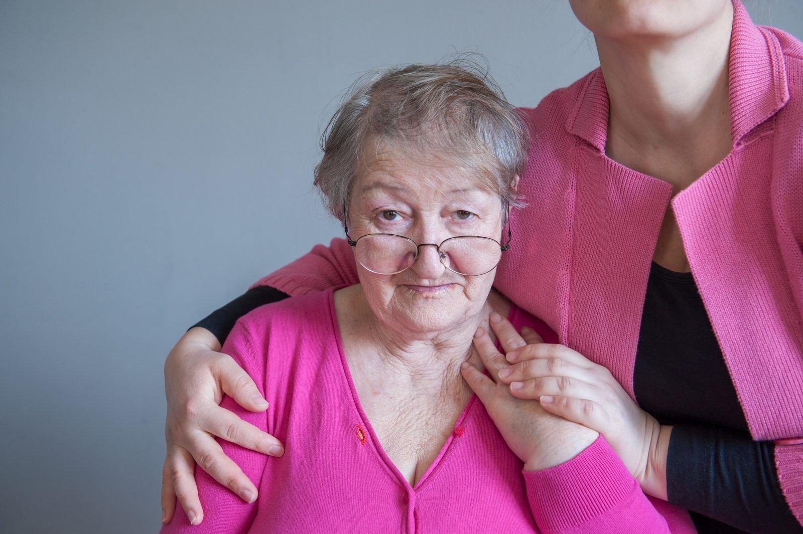 Cuidadora con la mano en el hombro de una señora mayor en casa